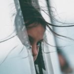 Girl looking out car window travelling away from home as immigrant