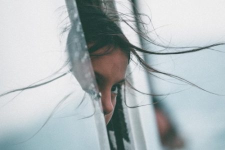 Girl looking out car window travelling away from home as immigrant